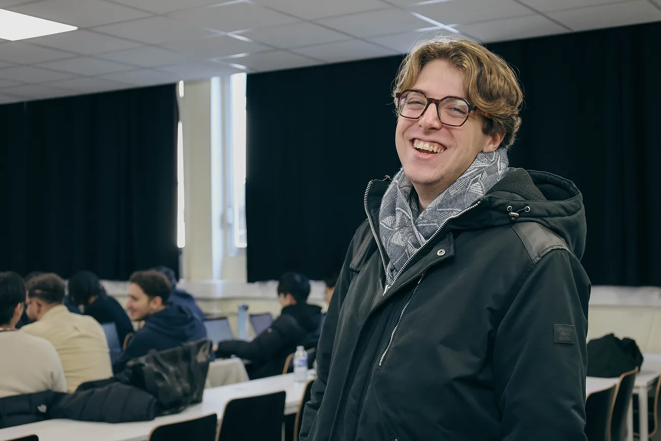 Etudiant en Mastère à HETIC, souriant devant sa salle de cours