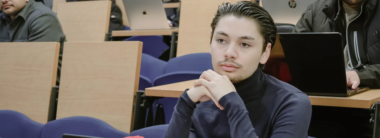 Étudiant suivant un cours à HETIC dans un amphithéâtre équipé d'ordinateurs portables